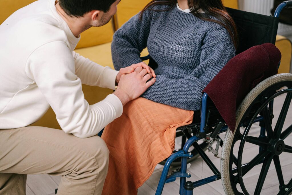 Dedicated caregiver from SWL Care Haven domiciliary care service provider attentively listening to a disabled service user while holding her hand, showcasing compassionate support and personalized care.