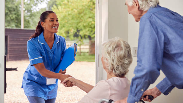 Senior couple warmly greeting a carer worker at their home, with the woman in a wheelchair