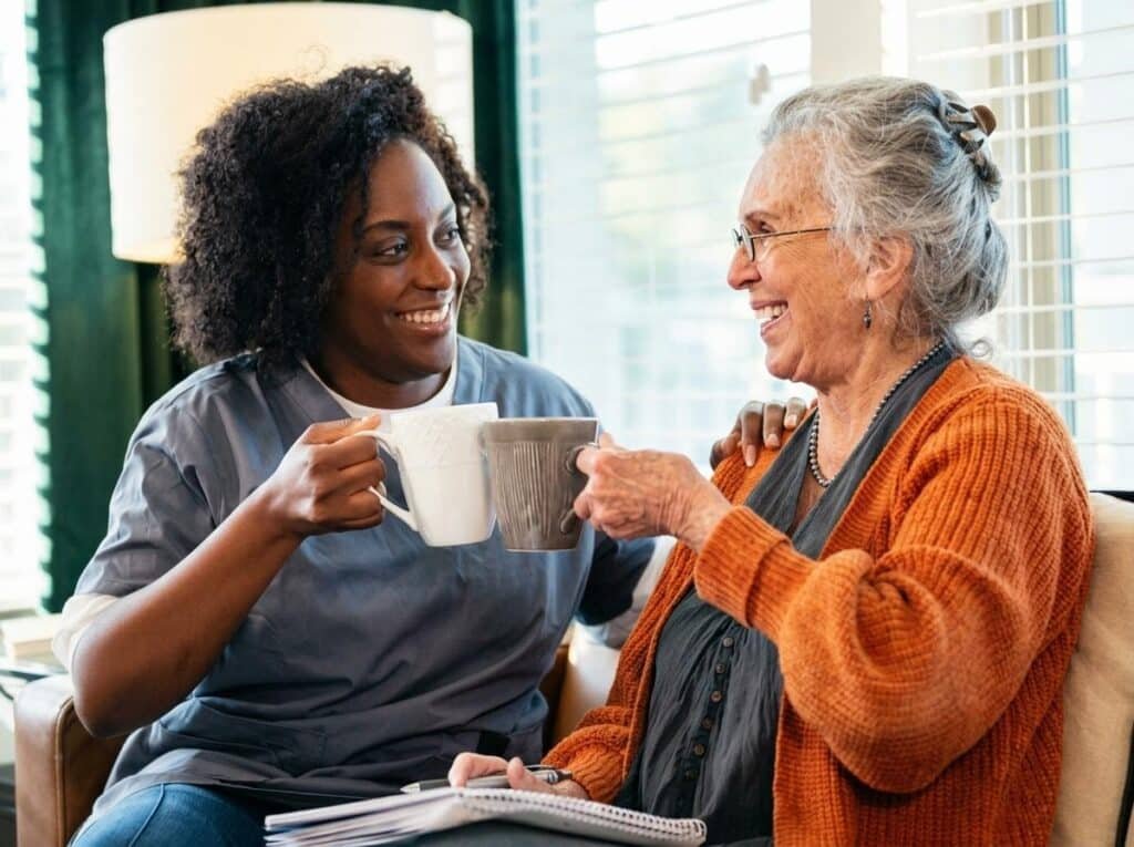 Compassionate carer and elderly woman sharing a warm drink in Croydon home.